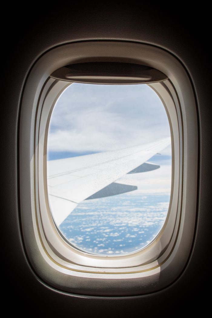 services-05 Captivating view through airplane window showing sky and plane wing.