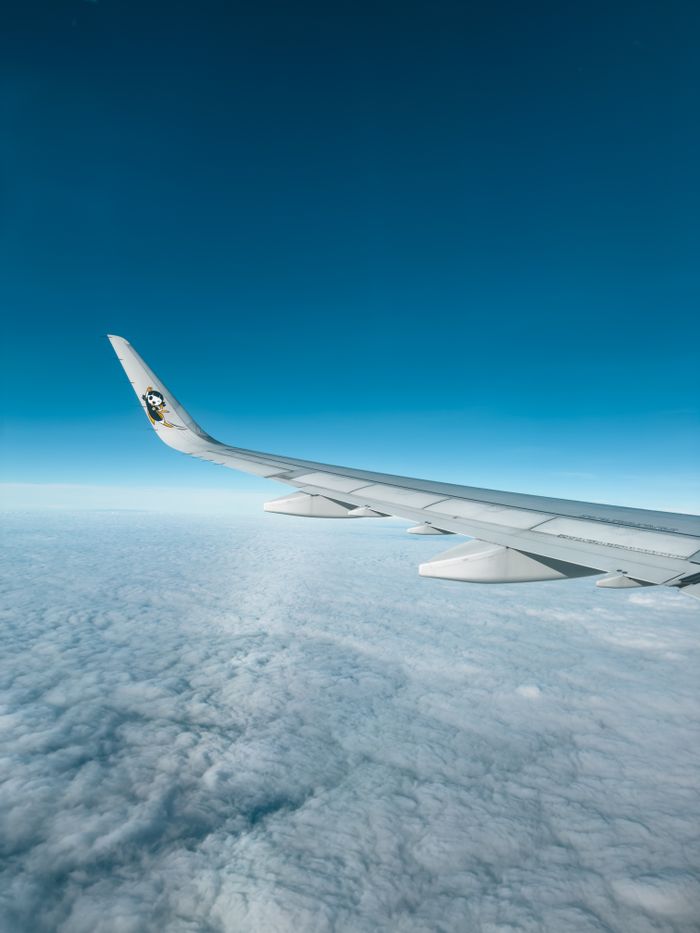 missions A panoramic view from an airplane, showcasing the wing and a vast sea of clouds below.