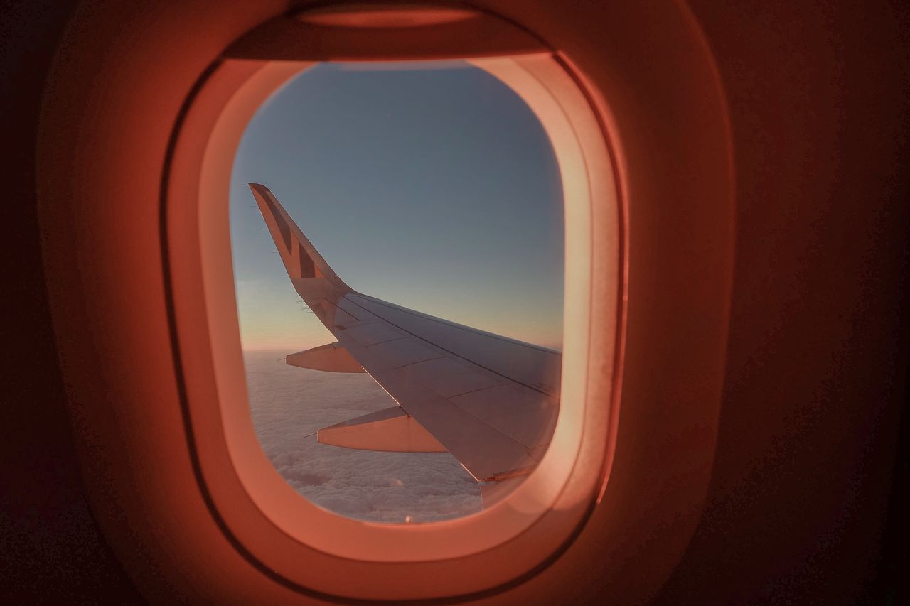 role-02 A serene view from an airplane window featuring a wing against a colorful sunset sky, evoking a sense of travel and exploration.